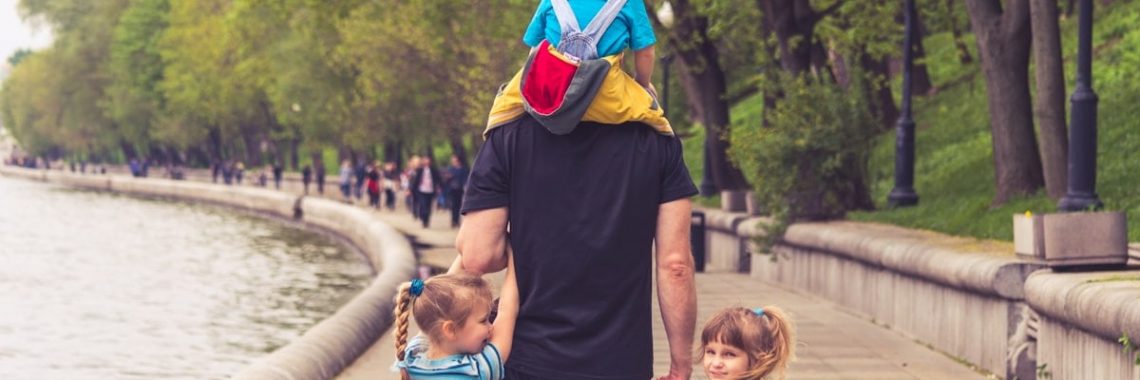 the father walks with three kids in the park